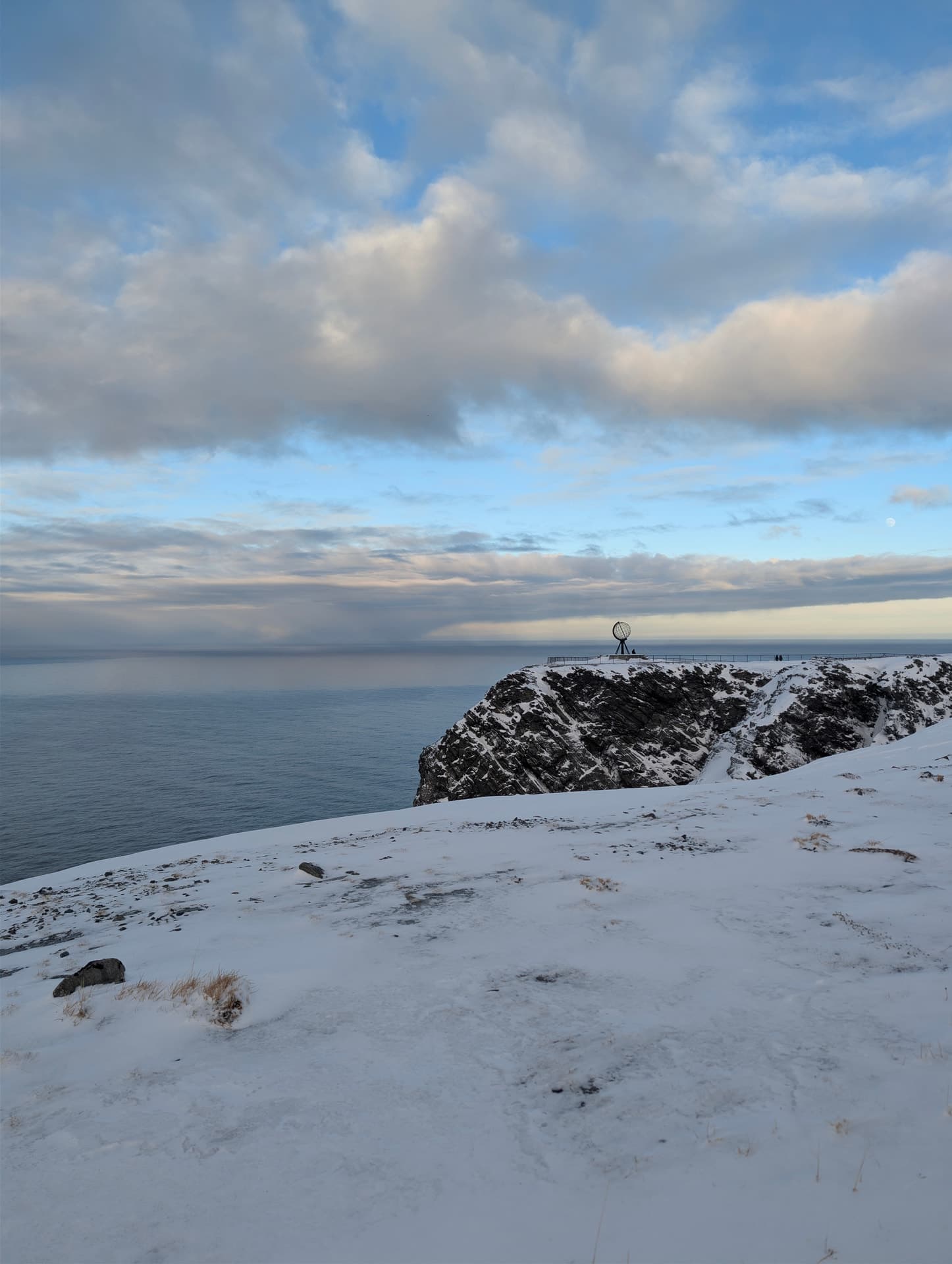 Die Erdkugel-Skulptur am Nordkapp im Winter unter blauem Himmel.