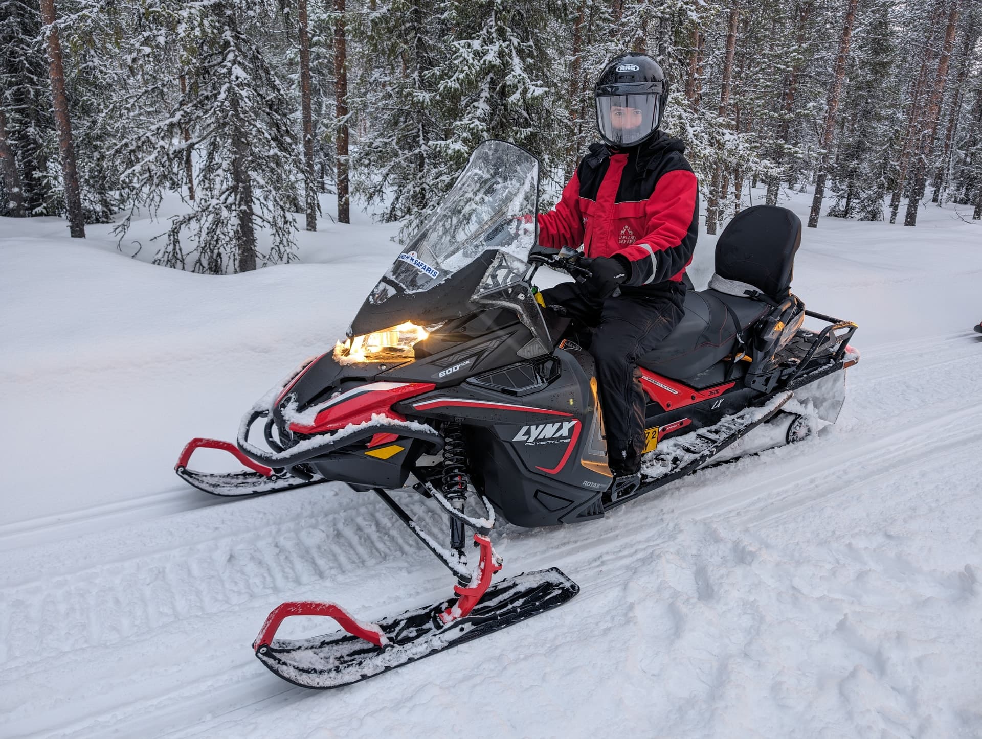 Schneemobil-Fahrer auf einer Lynx-Maschine im verschneiten Wald der Finnmark — eine der typischen Winteraktivitäten rund um Kokelv und Alta.
