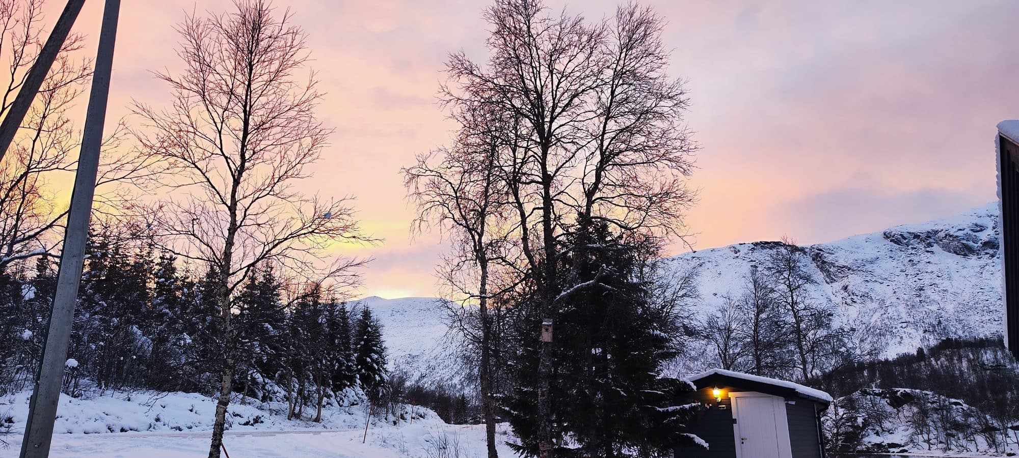 Zarter Pastellhimmel in Rosa und Orange über einer verschneiten Berglandschaft bei Narvik.