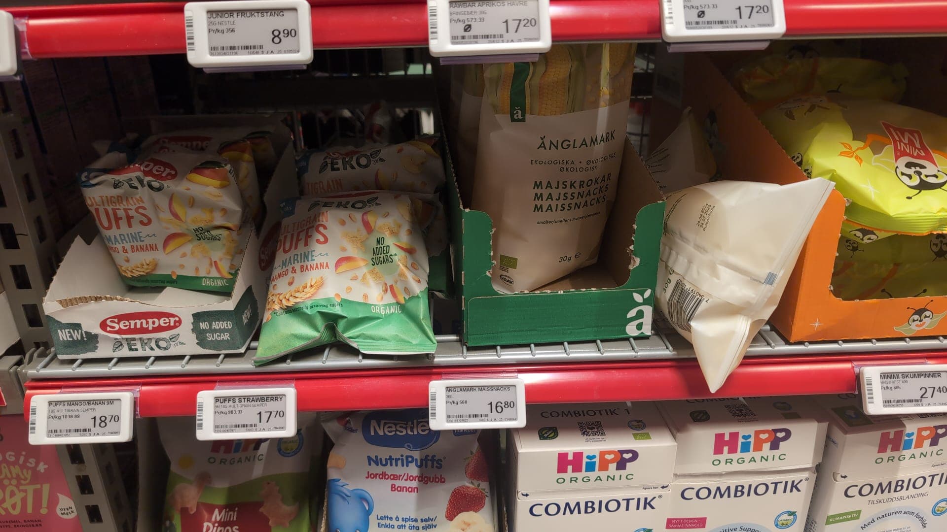 Regal in einem norwegischen Supermarkt mit Bio-Snacks und Babynahrung, gekennzeichnet mit digitalen Preisschildern in norwegischer Sprache.